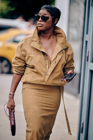 A NYFW SS25 Street Style guest wearing a tan zip jacket and tan skirt