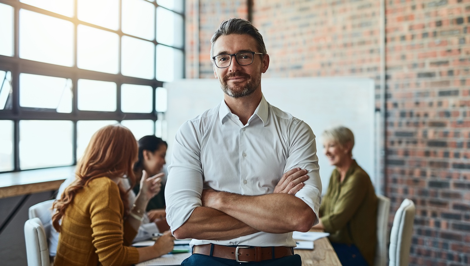 Cropped shot of a businessman standing in the office with his arms folded looking confident and smiling at the camera
