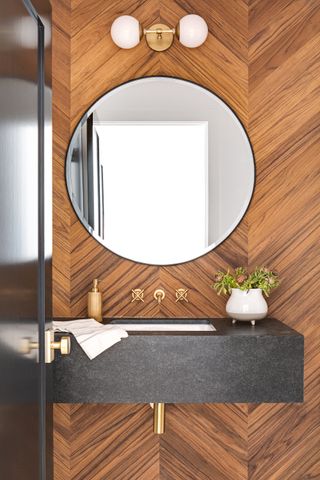 parquet wall powder room with grey quartz basin, round mirror, globe wall light