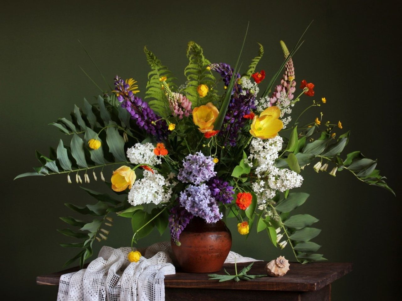 An old fashioned vase of flowers against a black background