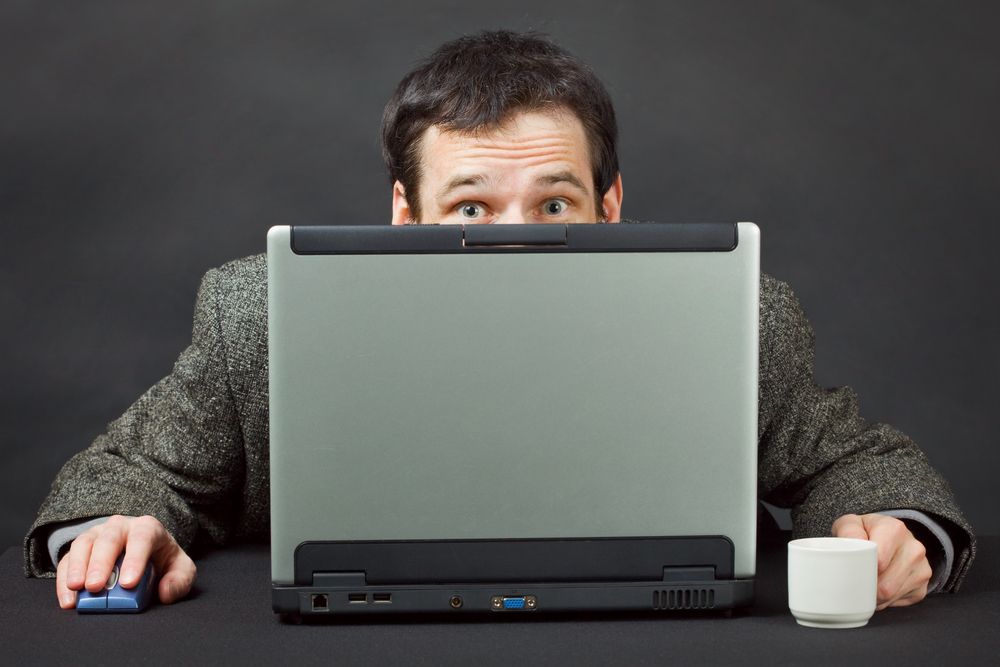 Man peering over computer 