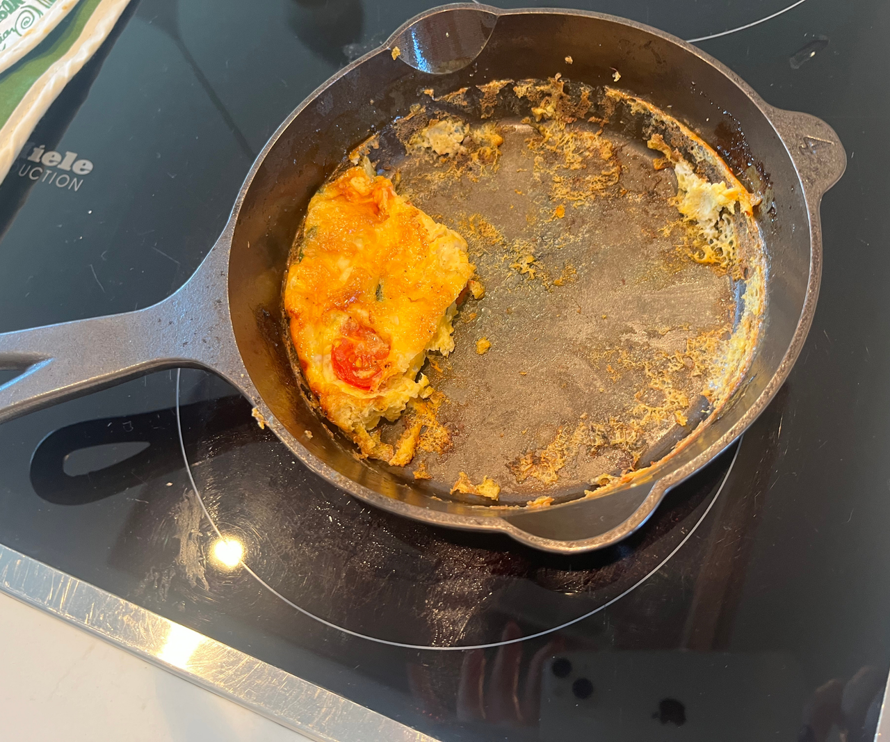 Lancaster Cast Iron Skillet on a stove with stuck on fritata inside.