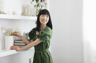 Marie Kondo arranging flowers in a vase on a shelf