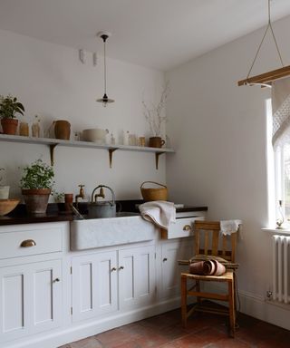 A white and gray modern rustic kitchen sink and cabinets designed by deVOL