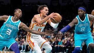 Trae Young #11 of the Atlanta Hawks goes to the basket while guarded by Terry Rozier #3 and Montrezl Harrell #8 of the Charlotte Hornets