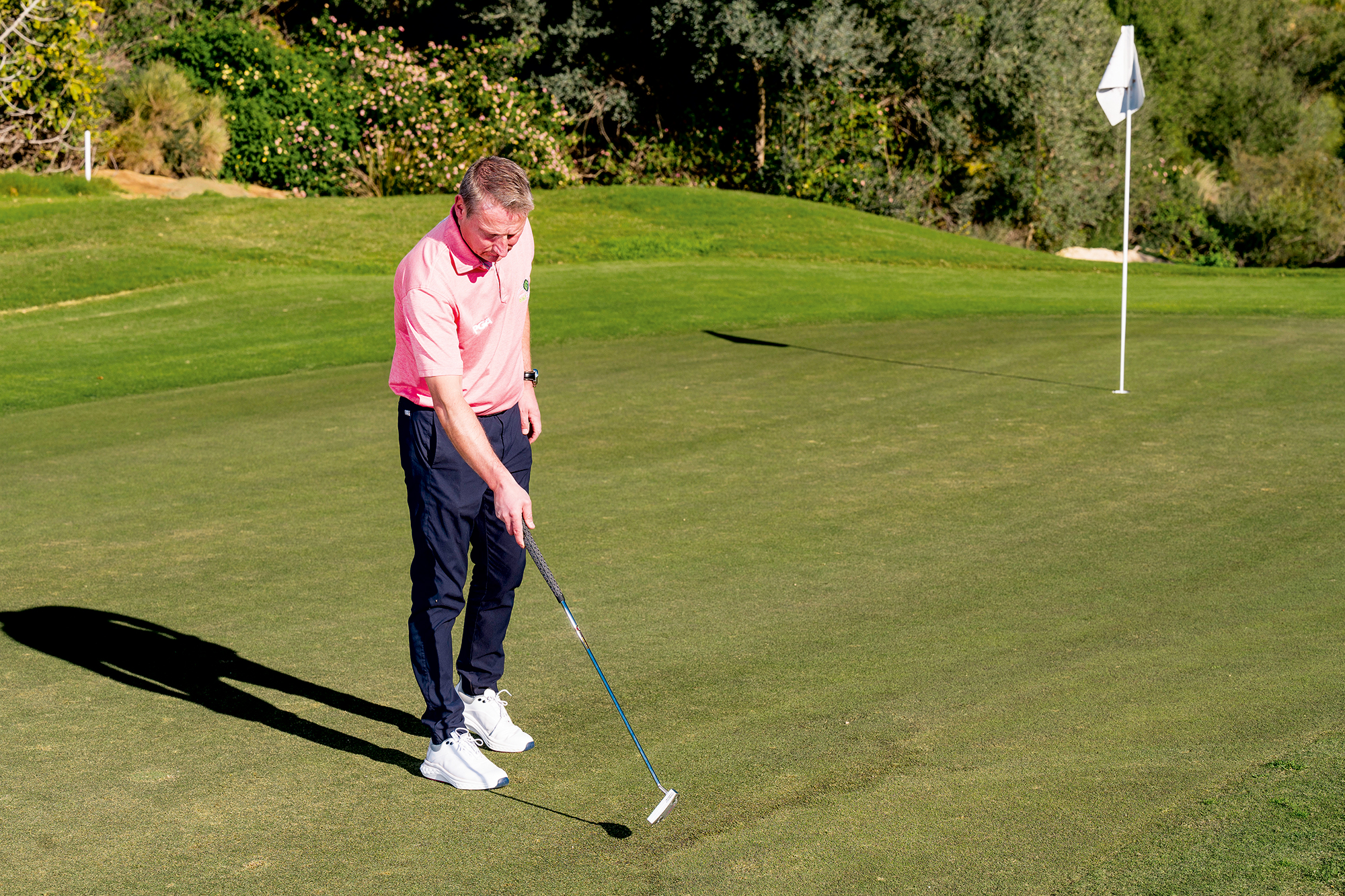 Anders Mankert pointing with his putter to the grain change on the green, the point where the grass goes from dark to shiny and indicating a change in speed