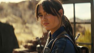 Lucy MacLean half-smiling in an outdoor setting in Fallout season 2