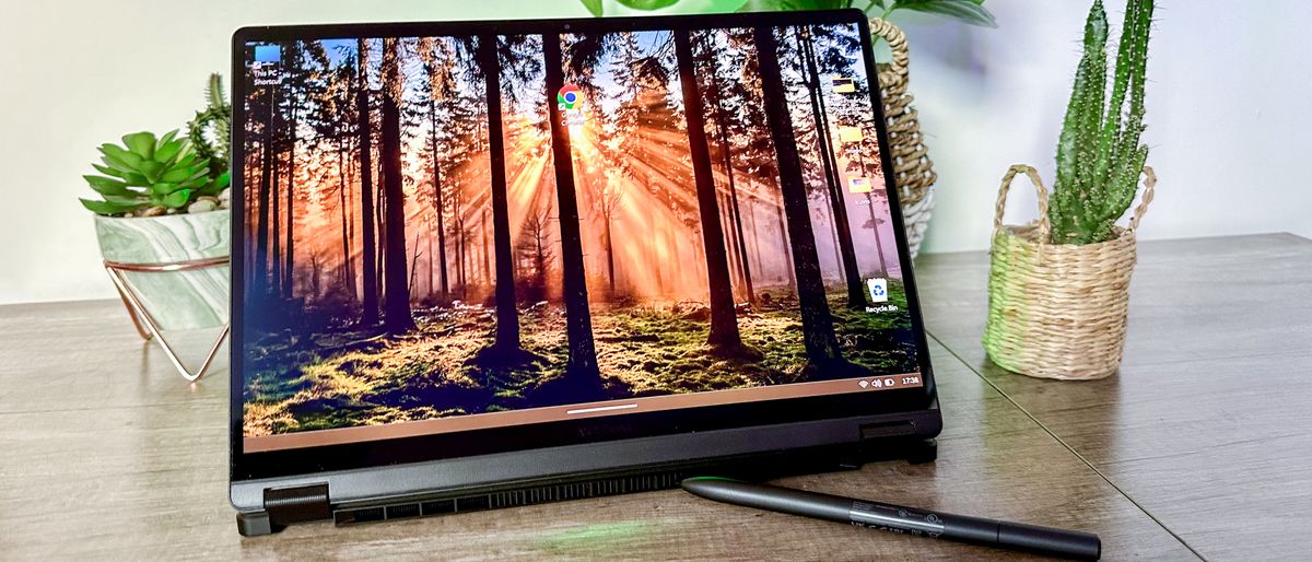 Asus ProArt PX13 on a desk with a desktop background of sunset in a wood