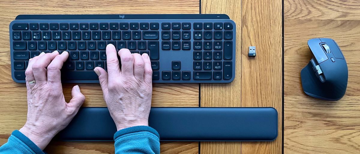 Hands typing on MX Keys S, with MX Master 3S mouse and MX Palm Rest