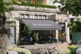 People sitting on café terrace outside Bodyism London gym and wellness centre