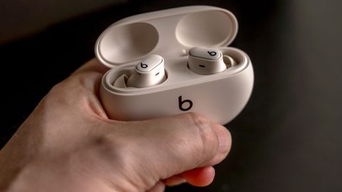 Holding the Beats Studio Buds Plus earbuds in open case.