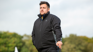 A golfer wears the Puma DRYLBL Waterproof Golf Jacket