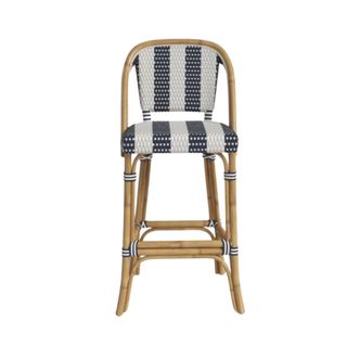 A rattan bar stool chair with a white and blue striped back and seat and light brown rattan arms and legs