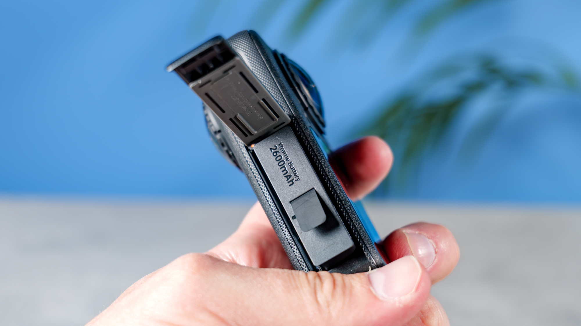 A photo of the Insta360 X6 in hand with its battery compartment open
