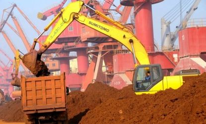 An excavator loads a truck with rare earth in Lianyungang city