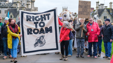 Protesters holding a banner that says 'right to roam' walk through Cirencester park