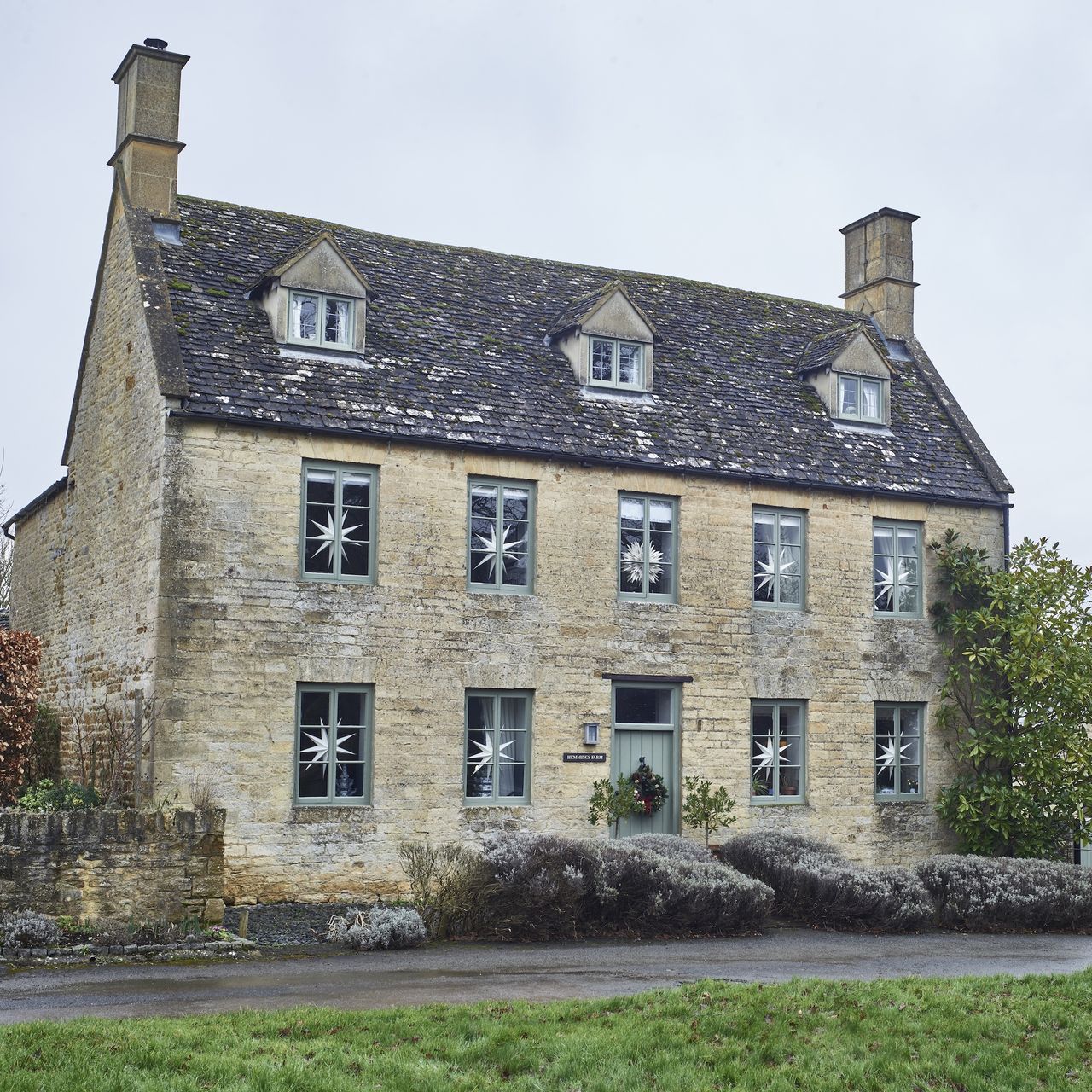 exterior of Cotswold house with Georgian facade and windows decorated with paper Christmas stars