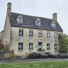 exterior of Cotswold house with Georgian facade and windows decorated with paper Christmas stars