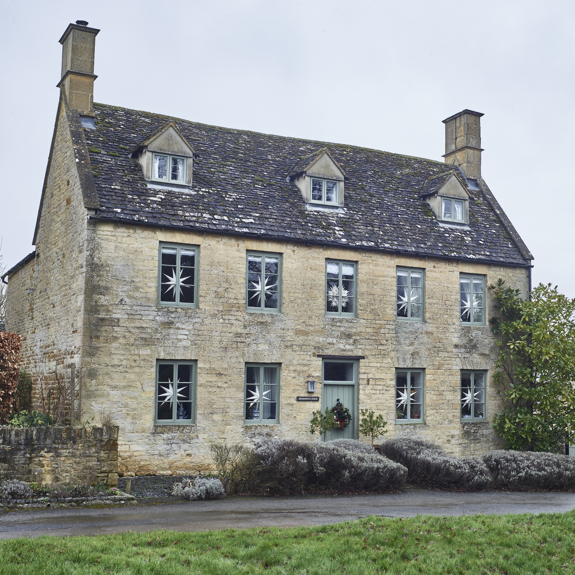 exterior of Cotswold house with Georgian facade and windows decorated with paper Christmas stars