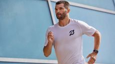 Man running with fitness tracker in Peloton t-shirt