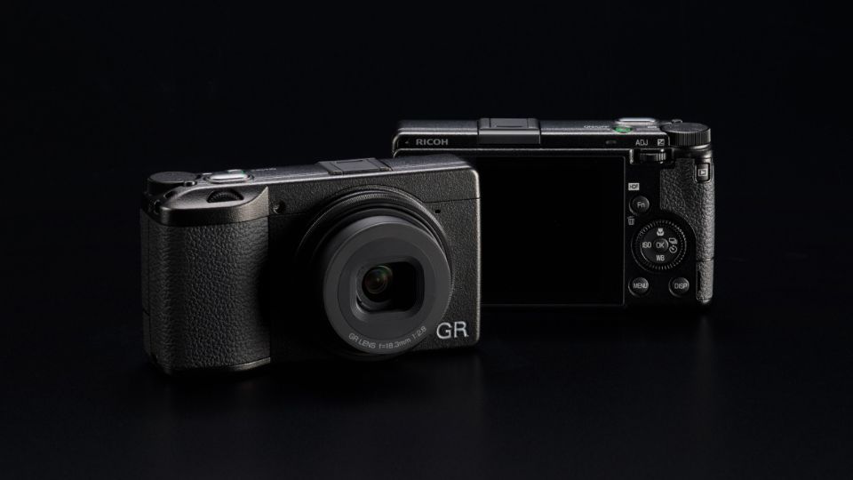 A pair of Ricoh GR III cameras, against a black background