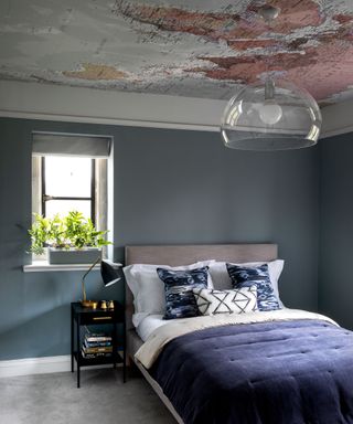 A gray teen bedroom with blue bedding and statement ceiling printed with a map of the world.