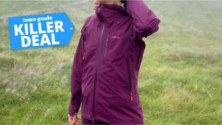 a picture of writer Jessica Downey wearing the Rab Firewall Mountain Waterproof Jacket with a Tom's Guide Killer Deal label on the top left corner
