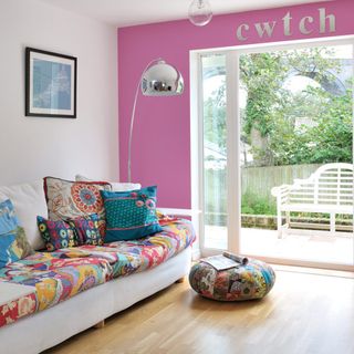 living room with french windows and sofa with cushions and pink wall