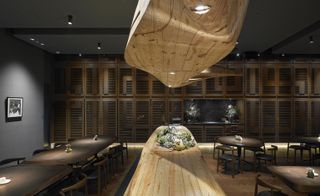 Raw restaurant with wooden island and bulkhead and wooden dining tables either side