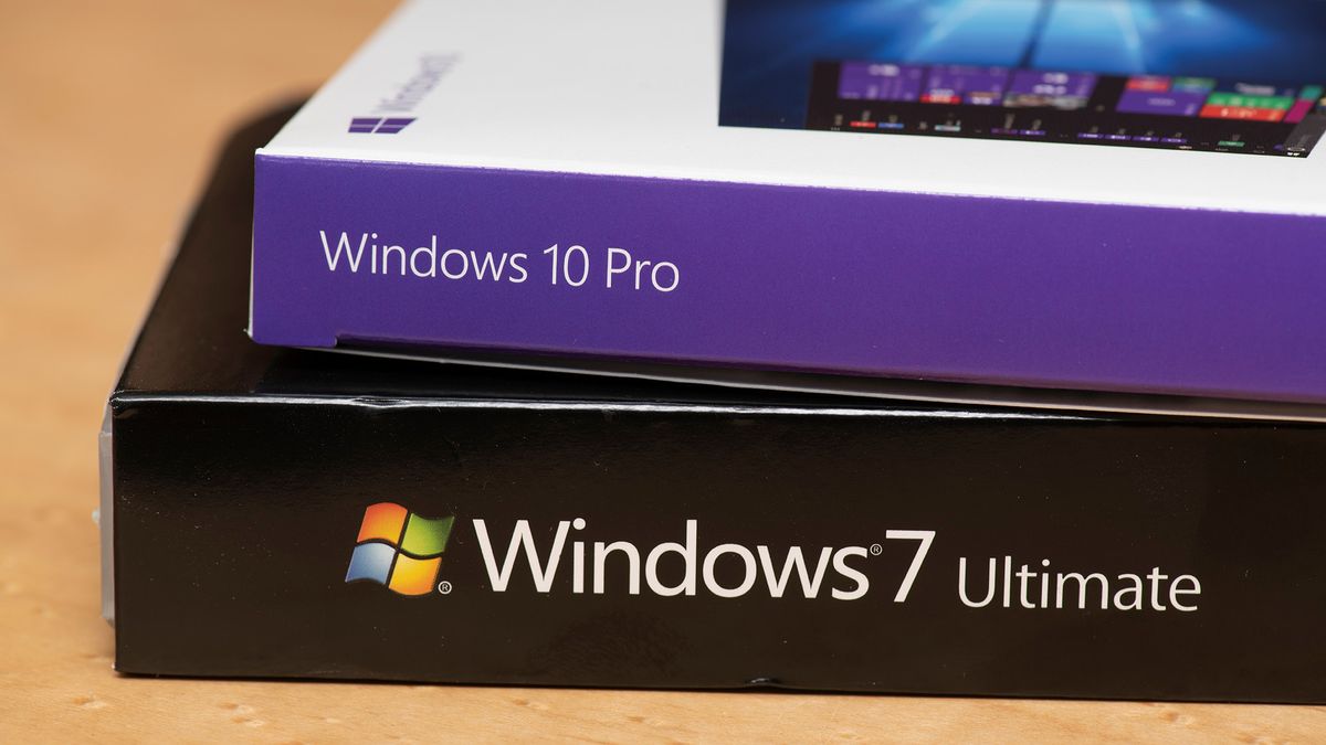 A Windows 10 Pro box lying on top of a Windows 7 Ultimate box, which is sitting on a table