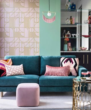 living room with blue sofa, bright cushions, pink footstool, retro gold and pink wallpaper, bar, gold side table