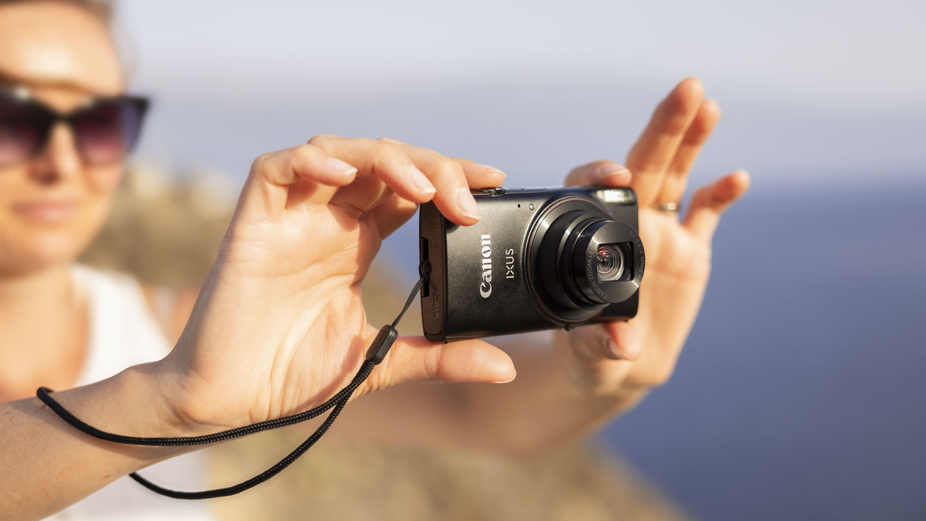 Canon PowerShot Ixus 285 HS A point and shoot camera in woman&#039;s hands, sunny outdoors