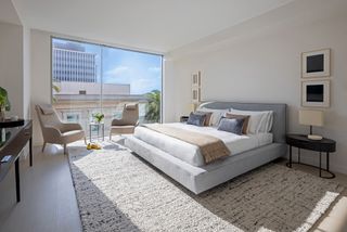 A neutral bedroom with a large floor to ceiling window