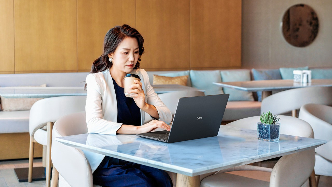 Dell Pro 14 laptop being used by a person sat at a table in a cafe