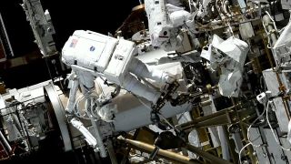 Astronauts perform a spacewalk outside the International Space Station.