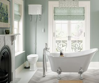 white freestanding bath and sink in pale green painted bathroom with black and white fireplace feature