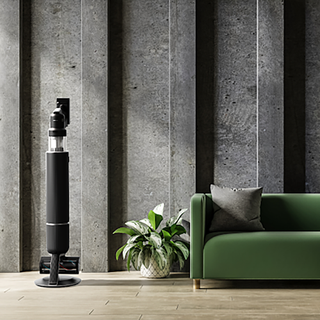 Samsung bespoke jet AI vacuum in black next to green sofa.