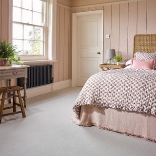 A bedroom with pink wall panelling on the walls and a carpet from the Turin collection by Riviera Home UK