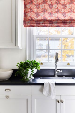 kitchen window with coral patterned roman blind sink and white walls