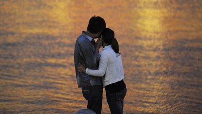 This picture taken on September 12, 2012 shows a couple embracing by a riverside in Tianjin. China's transient urban lifestyles have combined with frenetic social change, booming wealth and m