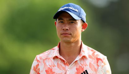 Collin Morikawa looks on with an orange floral shirt