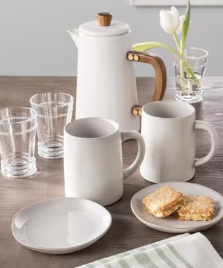 Two white coffee mugs and white pitcher on table