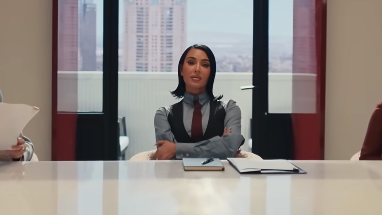 Kim Kardashian in a button down and vest sitting in an expensive office in All's Fair.