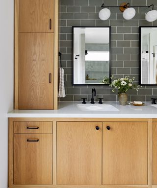 A bathroom with white oak cabinets and gray subway-tiled backsplash