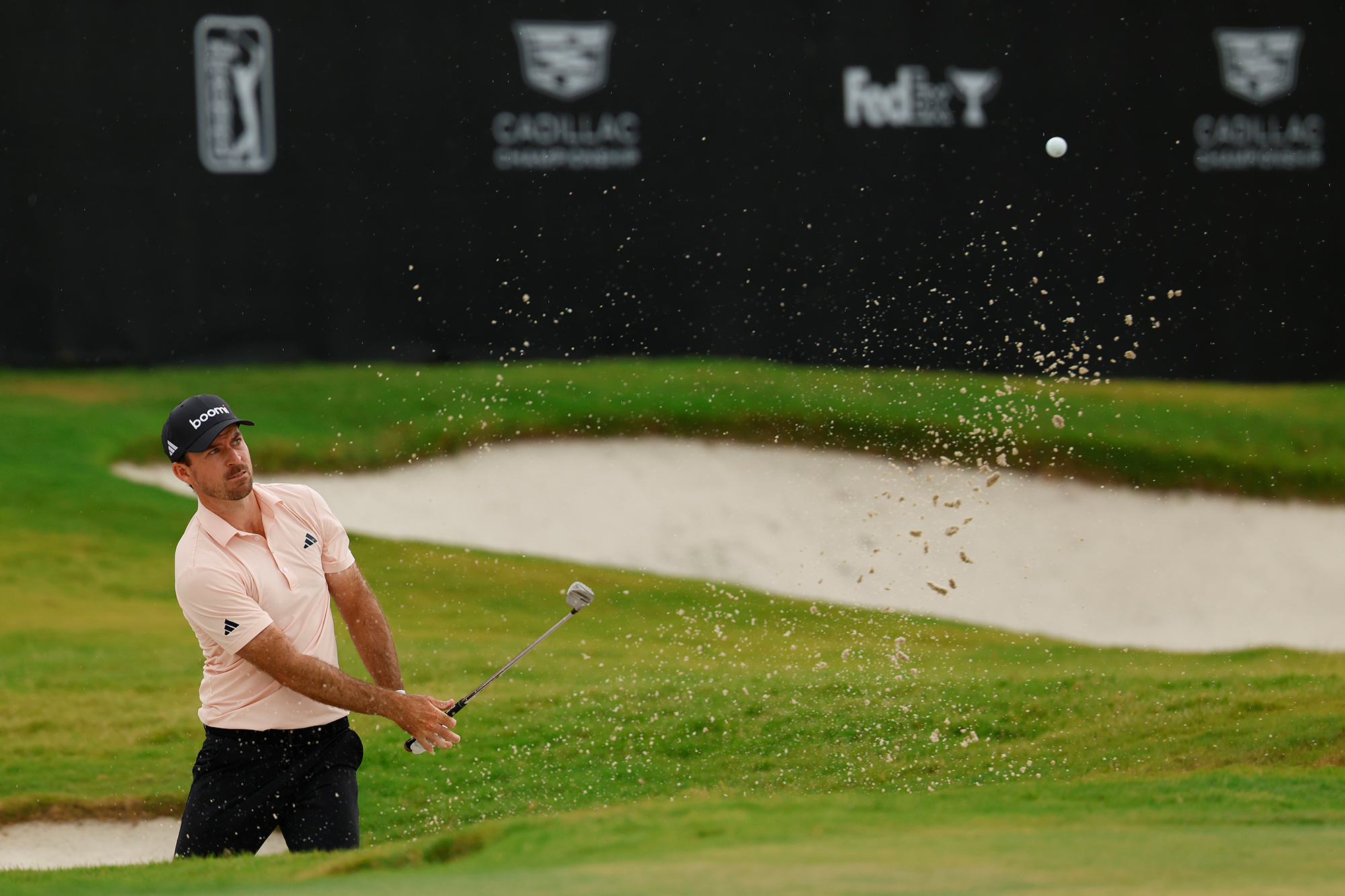 Nick Taylor hitting a bunker shot with sand flying around his ball in flight