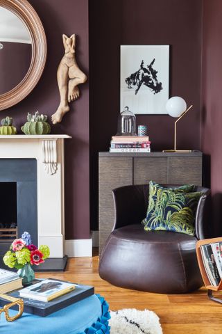 a deep purple living room with a purple wall, purple chair, and a wooden floor – with unique artwork on the walls and a white and black fireplace