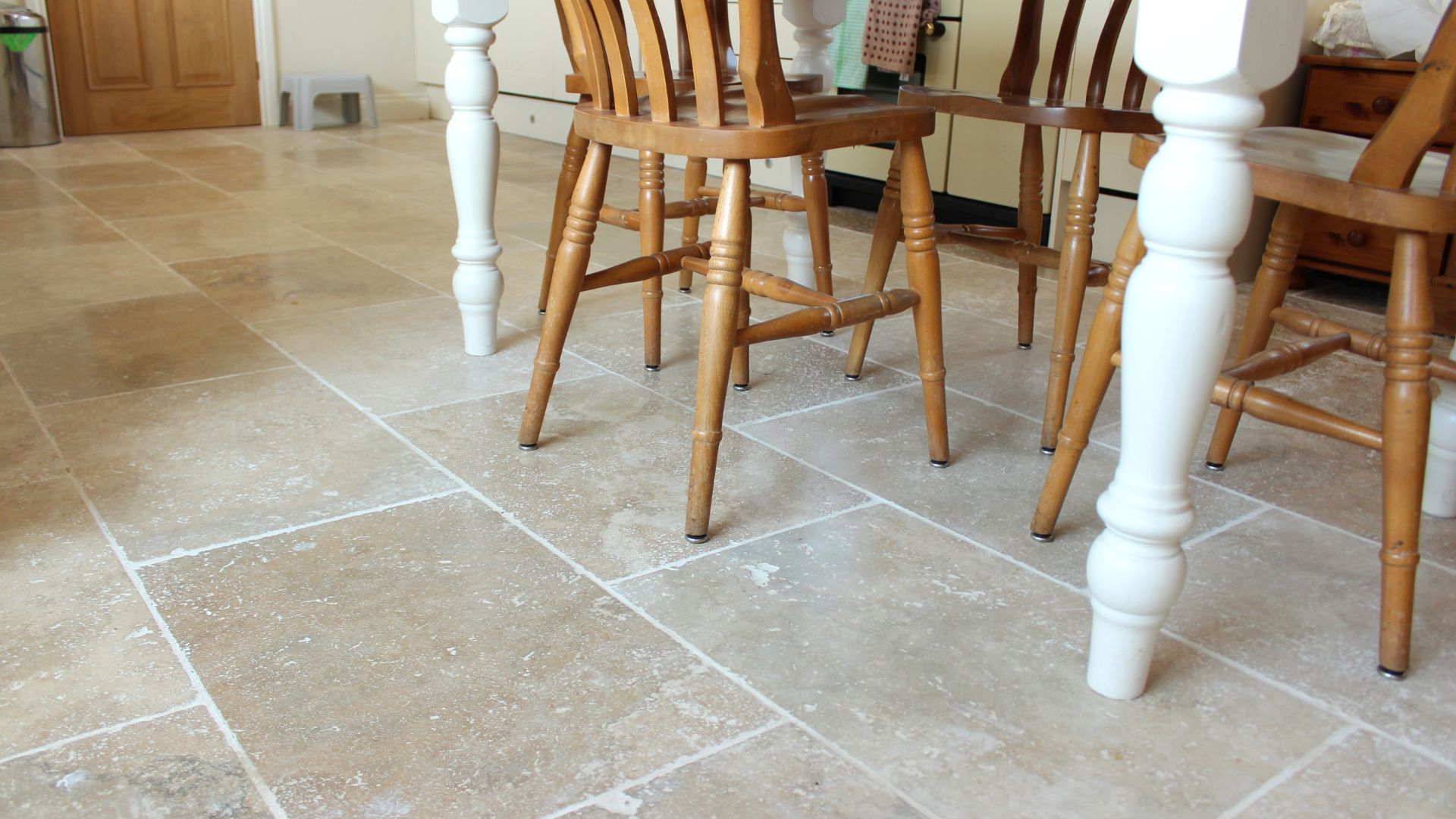 Image of filled travertine tile floor, kitchen table and chairs