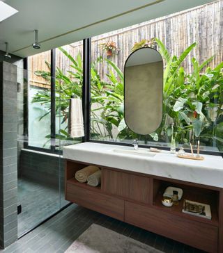 Vanity unit with glazing behind and tropical greenery outside