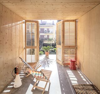 Natural sunlight penetrates the building through openings such as the wooden doors on the ground floor that lead out to the rear garden