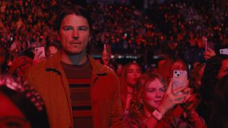 Josh Hartnett watches on with a scoul while Ariel Donoghue watches happily through her phone in Trap.